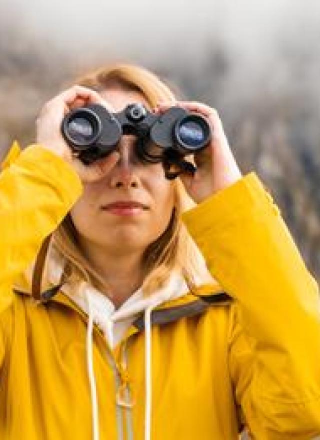 woman looking up through binoculars