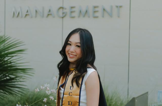 Diana Tran wearing a graduation stole, standing in front of Gallagher Hall