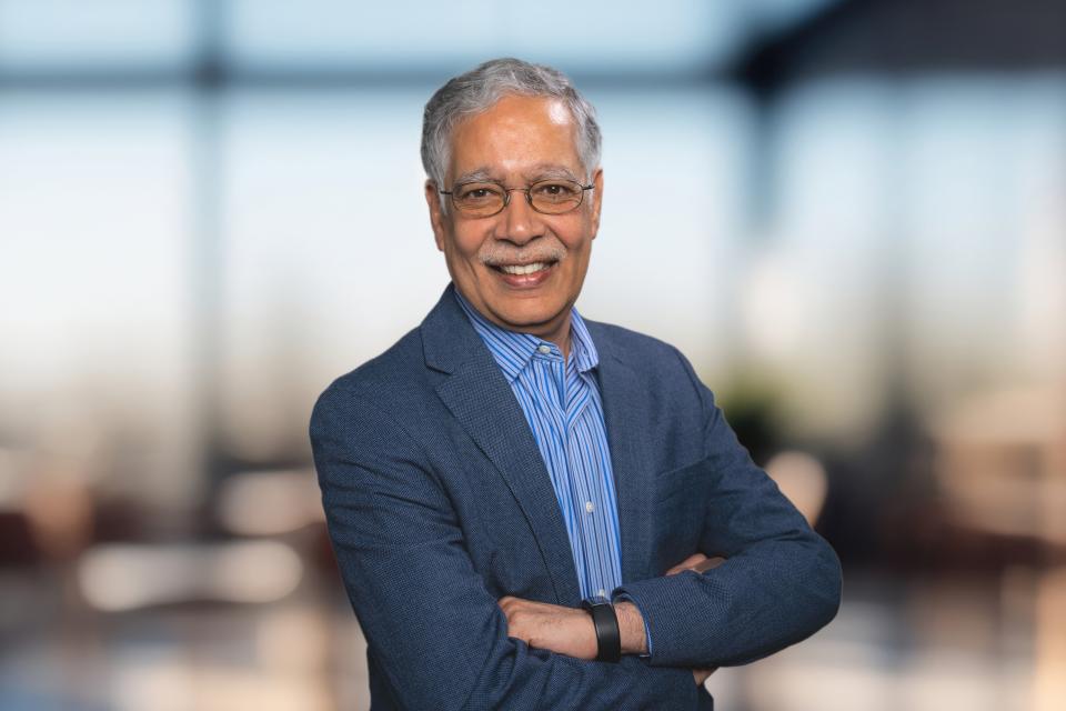 Dean Unnava posing in front of the UC Davis seal