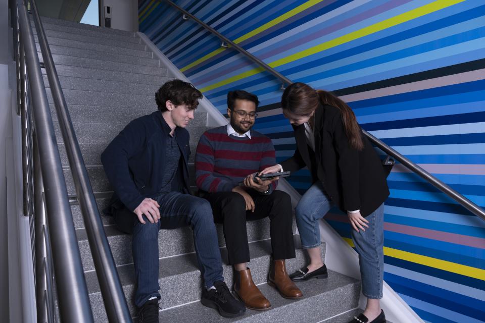 Group of individuals sitting on stairs looking at a tablet
