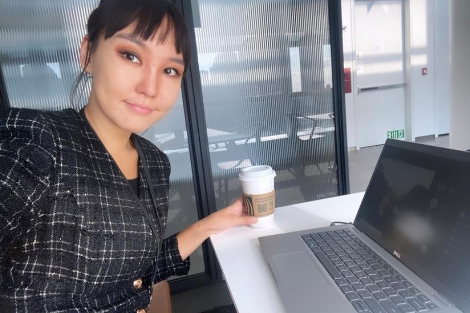 Sodontuya Nerguidavaa sitting in front of a laptop with a coffee in hand