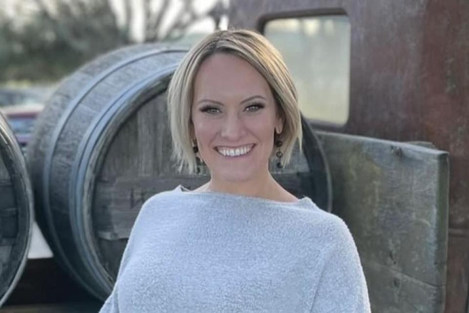 Natalie Frazier in front of wine barrels